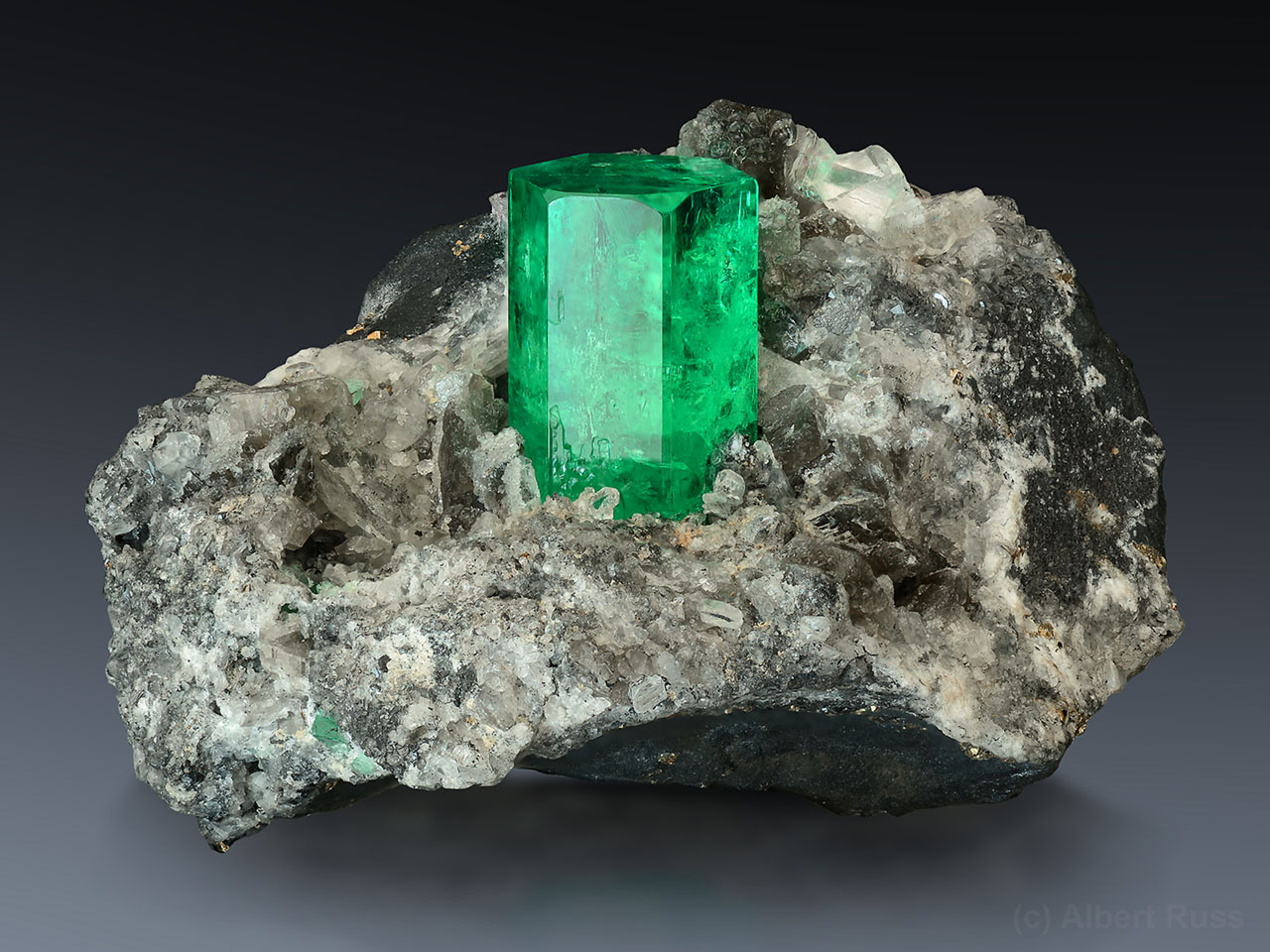 Sytě zelený drahokamový smaragd s kalcitem z lokality Coscuez Mine v Kolumbii. 