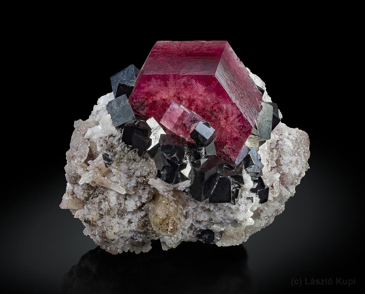 Červený beryl (bixbit) s černými krystaly bixbyitu a světlým topazem z lokality Searl Canyon, Red Beryl Claim, Juab Co., Utah, USA